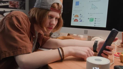 Tired Teenager Using Smart Speaker with Smartphone while Studying at Home Stock Footage 340795310