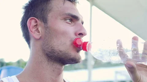Tired of training the athlete sits on a bench and drinking water Stock Footage 56229026