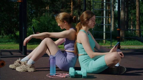 Tired twin sisters using smartphones after workout Vídeos de archivo 336960902