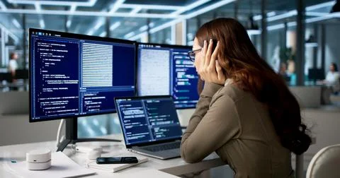 Tired Web Developer Sits At Desk Coding With Sad, Frustrated Face. Stock Photos