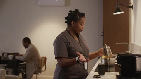 Tired Woman Preparing Tea while Her Husband Working on Laptop Stock Footage 328515100