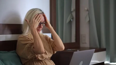 Tired Woman Removing Glasses While Working Remotely in Her Bedroom Stockbeeldmateriaal 342525320