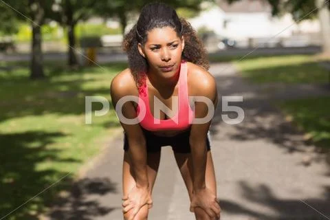 Tired woman taking a break while jogging in park Stock Photos