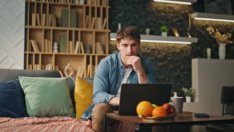 Tired worker focused laptop solving problem at home couch. Freelancer working Stock Footage 253719537