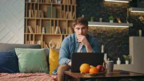 Tired worker focused laptop solving problem at home couch. Freelancer working Stock Photos