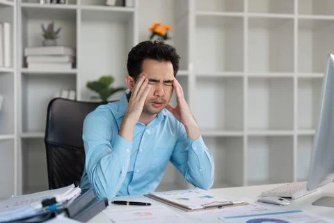Tired worker overcomes hard work challenges at office desk stressful environment 库存照片