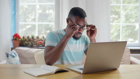 Tired young afro man working at home office on new project Stock Footage 133043627