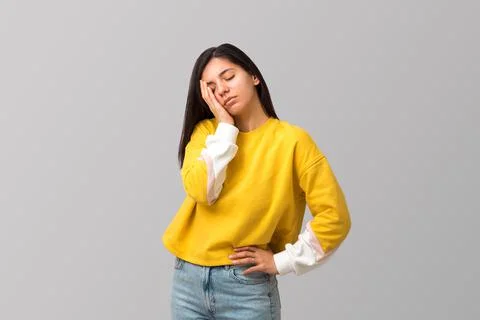 Tired young attractive multi ethnicity woman in trendy yellow sweater against Stock Photos