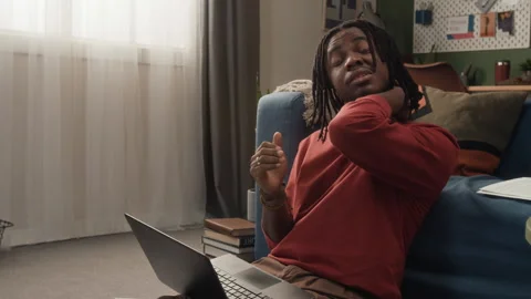 Tired Young Black Man Stretching Neck while Working Online on Laptop at Home Stock Footage 328249900