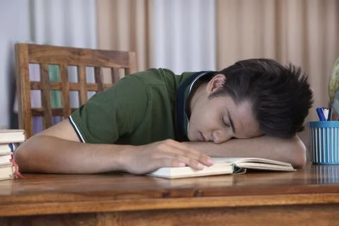 A tired young boy sleeping while studying for competitive examination - Study... Stock Photos