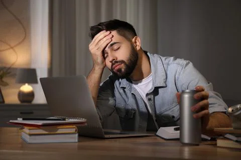 Tired young man with energy drink studying at home Stock Photos