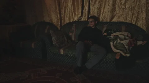 Tired young man falling asleep on the sofa Vidéo 330564627
