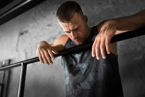 Tired young man at parallel bars in gym Stock Photos