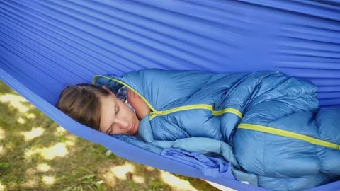 A tired young man sleeping in hammock in sleeping bag Stock Footage 151129870