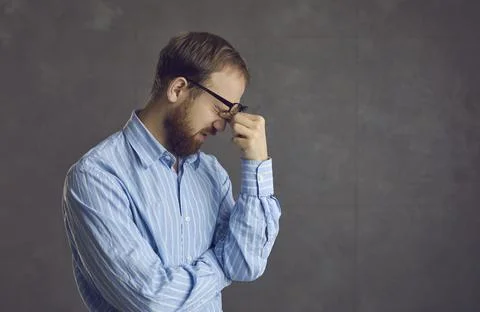 Tired young man suffering from computer eye strain rubbing his sore eyes after Stock Photos