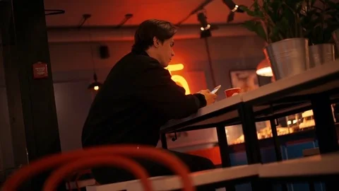 Tired young man using smartphone in bar in the evening Stock Footage 77168562