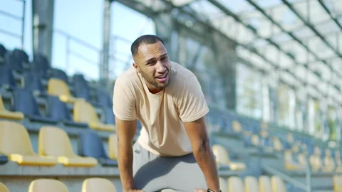 Tired young runner has shortness of breath after running in urban city stadium.  Stock Footage 234880324