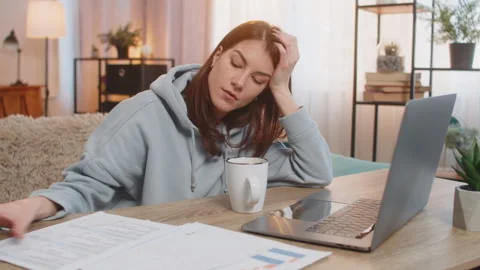Tired young woman freelancer using laptop computer at table with documents in Stock Footage 315912369