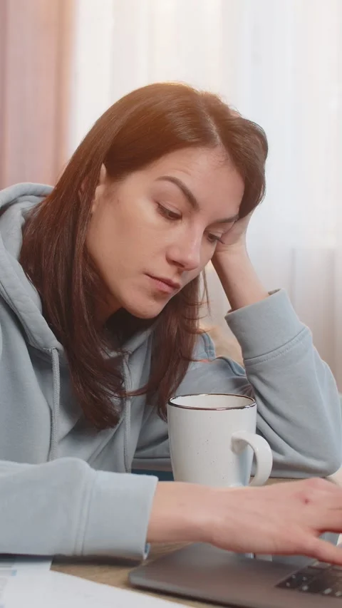 Tired young woman freelancer using laptop computer at table with documents in Stock Footage 320784220