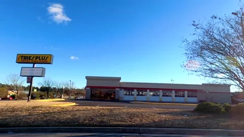 Tires Plus auto store pan POV FPV side building view Stock Footage 148101299