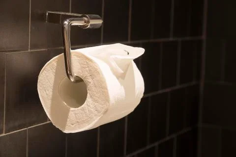 Tissue roll adjacent to the black wall. Stock Photos