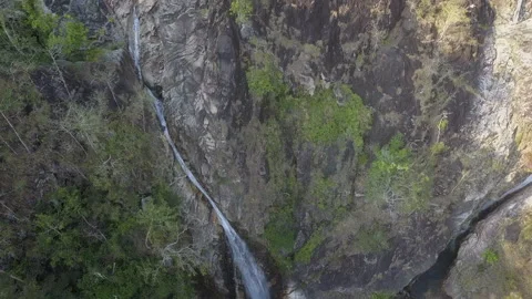 Title: Large foaming waterfall falls from rocky cliff with moss. Stock Footage 156642481