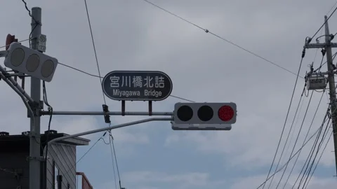Title: Miyagawa Bridge Intersection Sign and Traffic Lights Against Cloudy Sky Stock Footage 339915653