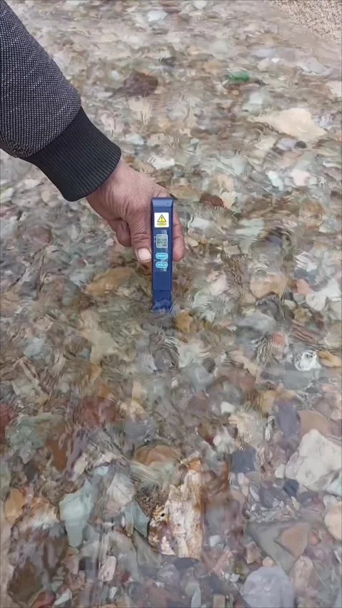 Title: Testing Water Purity with Digital TDS Meter in a Natural Stream Stock Footage 332620947