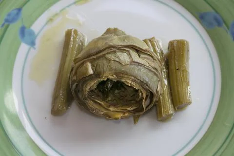 TITLE:.Cooked artichoke with stems served on a patterned plate Stock Photos