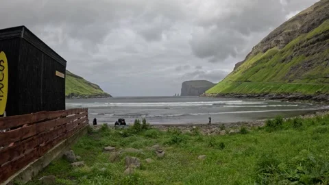 Tjornuvik surf cabin side view with tourists on the beach, Faroe Islands Stock Footage 339713089