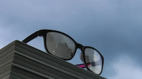 T/L Glasses and books with cloudscape time lapse view Stock Footage 164007950