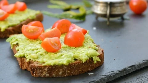 Toast with avocado, cherry tomatoes and spices Stock Footage 72587323