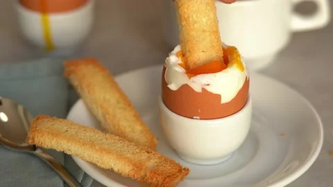 Toast bread dips in soft-boiled egg. Crispy crouton with boiled egg. Breakfast Stock Footage 163509111