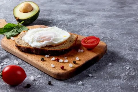 Toast bread with eggs, cherry tomatoes, avocado and greens on wooden cutting  Stock Photos