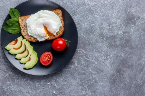 Toast bread with eggs, cherry tomatoes, avocado and greens on wooden cutting  Stock Photos