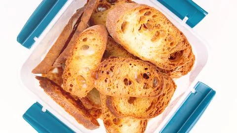 Toast in a plastic container on a white background. Toasted baguette slices Stock Photos