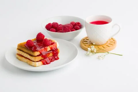 Toast with raspberry jam and cup of tea on beige table. Stock Photos