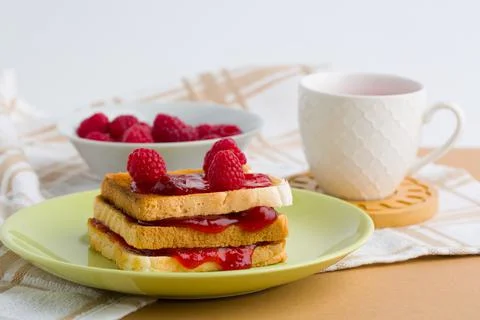 Toast with raspberry jam and cup of tea on beige table. Stock Photos