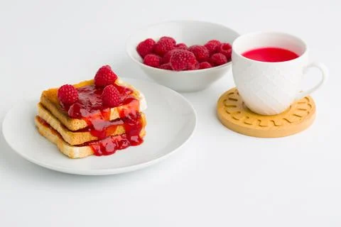 Toast with raspberry jam and cup of tea on beige table. Stock Photos
