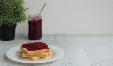 Toast with raspberry jam on a white table, space for text Stock Photos