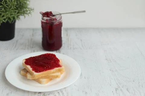 Toast with raspberry jam on a white table, space for text Stock Photos