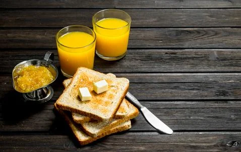 Toasted bread with butter, orange jam and juice. Stock Photos