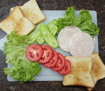 Toasted bread, ham, fresh cucumbers and tomatoes, and fresh lettuce Stock-Fotos