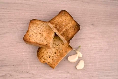 Toasted bread slices with appetite crispy crust and few garlic cloves Stock Photos