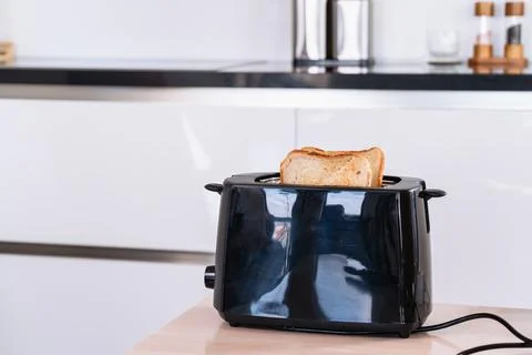 Toasted Bread Slices Popping Up From Electric Toaster Фото