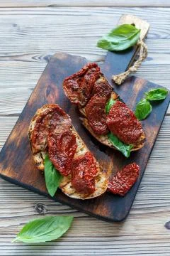 Toasted bread with sun dried tomatoes and basil. Stock Photos