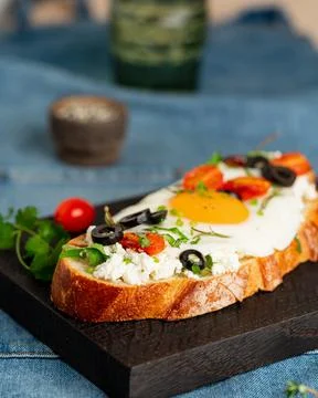 Toasted bread toast with fried eggs with yellow yolk and tomatoes, vertical Stock Photos