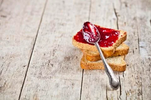 Toasted cereal bread slices stack with homemade cherry jam and spoon closeup  Stock Photos