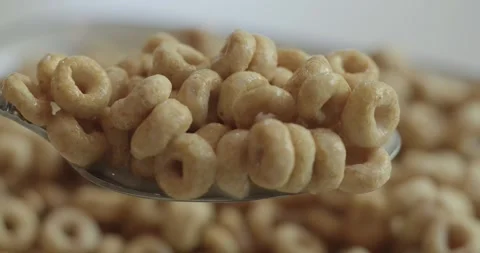 Toasted oat ring cereal rests on a spoon in macro 库存影片 342450835