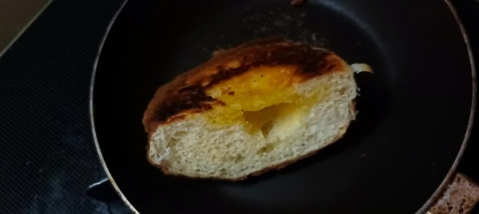 Toasted or fried bread slice in a black frying pan Stock Photos